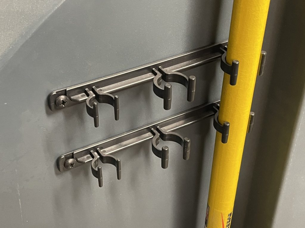 Molded clip bracket on a cleaning cart holding a mop handle